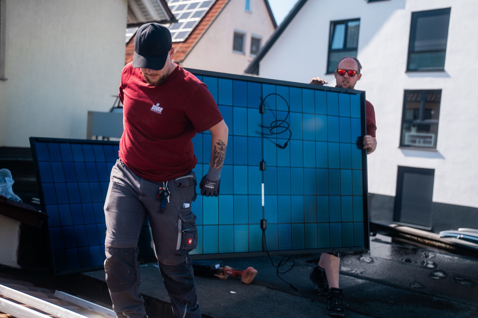 Dürr-Monteure tragen ein Solarmodul aufs Dach